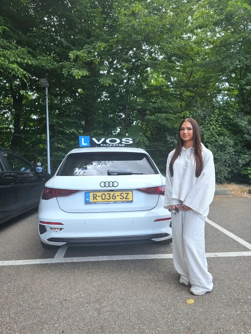 Geslaagde vrouw naast de witte lesauto